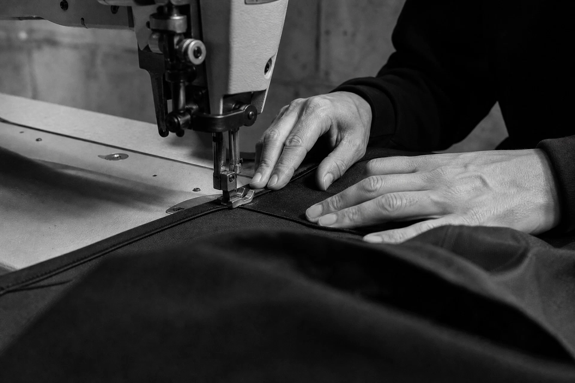 Artisan constructing a black garment on an industrial sewing machine